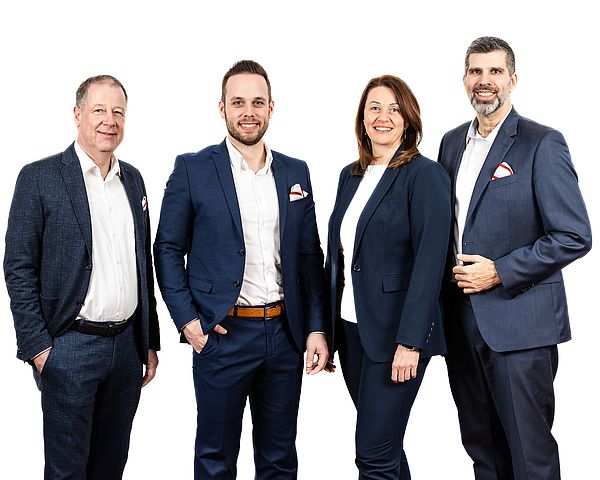 Michael Schlögl, Dominic Krb, Karin Reisenauer und Peter Kirisics lächeln im Business Look in die Kamera